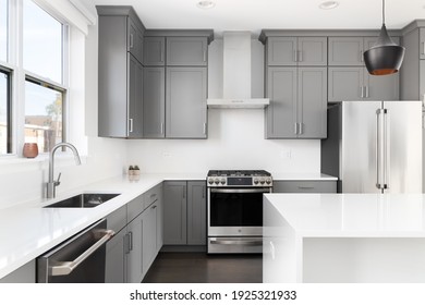 OAK PARK, IL, USA - NOVEMBER 1, 2020: A Modern Kitchen With Grey Cabinets, A Bowl Of Lemons On The White Granite Counter Tops, And Dark Hardwood Floors.