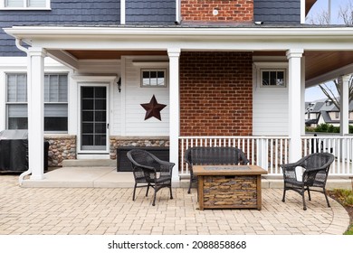 OAK PARK, IL, USA - NOVEMBER 1, 2021: The Back Patio Of A Blue And White Modern Farmhouse With A Stone Patio, Covered Porch, And A Brick Chimney.