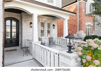 OAK PARK, IL, USA - NOVEMBER 4, 2021: The Front Of A Modern Farmhouse With White Pillars, A Fenced In Seating Area, And A Wood And Glass Front Door.