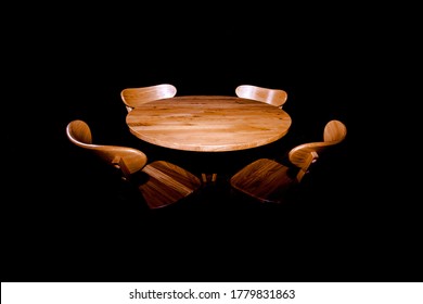 Oak Round Table And Four Chairs Around In The Dark On A Black Background