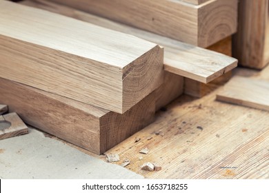 Oak wooden bar blocks materials stacked at carpentry woodwork workshop with tools and sawdust on background. Timber wood blanks at diy workbench. Close-up lumber beam details. Handcraft hobby