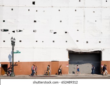 OAKLAND, CA - Aug.20, 2016: Tech Giant Uber New Headquarters Building Under Construction. White Shrink Wrap. People Walking By Show The City's Changing Demographics Amid Concerns About Gentrification.