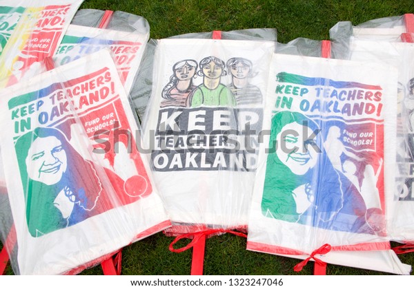 Oakland, CA - February 25, 2019: Signs covered\
in plastic to protect from rain for Oakland teachers strike day 3\
rallying at Frank Ogawa Plaza. Fighting for smaller class sizes and\
bigger paychecks.