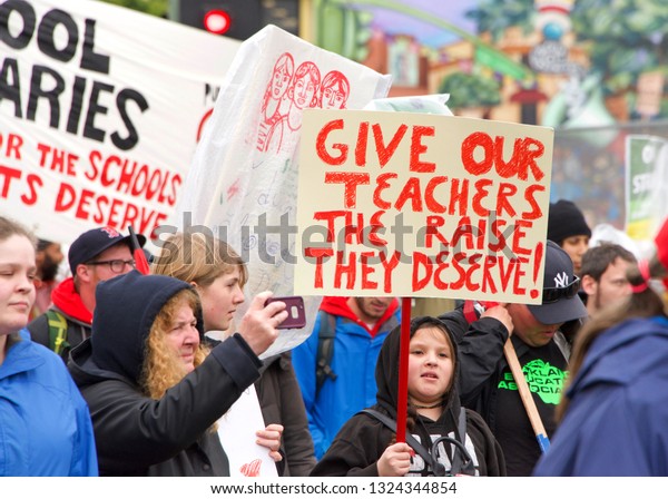 Oakland, CA - February 26, 2019: Unidentified\
participants in Oakland teachers strike day 4 marching down 98th\
street to Roots Academy. Fighting for smaller class sizes and\
bigger paychecks.