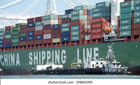 OAKLAND, CA - JULY 13, 2015: China Shipping Lines Cargo Ship SUMMER Loading At The Port Of Oakland With Tugboat ROYAL MELBOURNE Securing A Barge Ship Up Beside The Vessel To Provide Maritime Services.