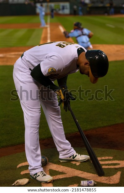 Oakland, California - July 5, 2022: Oakland\
Athletics outfielder Chad Pinder puts pine tar in his back in the\
on deck circle during a game against the Toronto Blue Jays at the\
Oakland Coliseum.