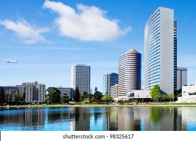 Oakland, California. View across Lake Merritt with beautiful reflections of buildings on the water's edge.  There is a blimp in the sky.