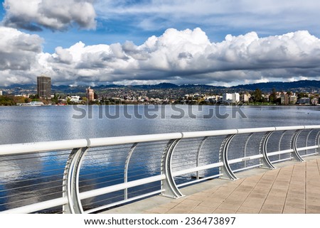 Oakland California view across Lake Merritt of the north shore and the Oakland Piedmont hills, on a day with dramatic storm clouds reflected in the water. Viewed from the new south shore bridge area.