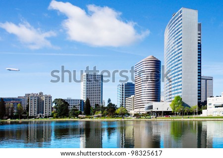 Oakland, California. View across Lake Merritt with beautiful reflections of buildings on the water's edge.  There is a blimp in the sky.