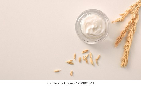 Oat Body And Facial Moisturizer Cream In Glass Jar With Spikes On White Table. Top View. Horizontal Composition.