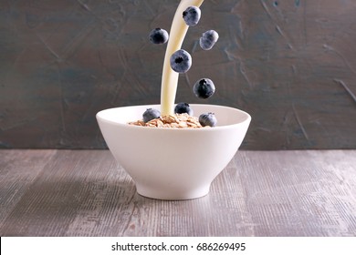 Oat Flakes With Falling Blueberry And Pouring Milk From Above