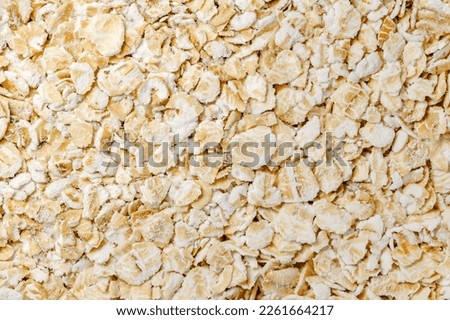 Oat flakes raw, steamed and flattened croup in bulk, close-up, background wallpaper, uniform texture pattern