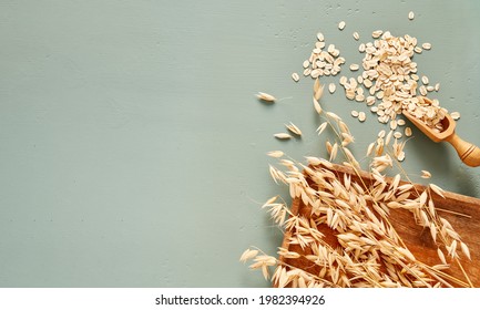 Oat flakes in wooden spoon and ears of oat on blue background. Flakes for oatmeal and granola. - Powered by Shutterstock