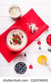 Oat Fruit Breakfast In Red Bowl Top Down View. Blueberry Raspberry And Honey In Yogurt Cooked Cereal Flake Porridge Organic Morning Energy Food. Oatmeal Muesli Ingredient Healthy Lifestyle