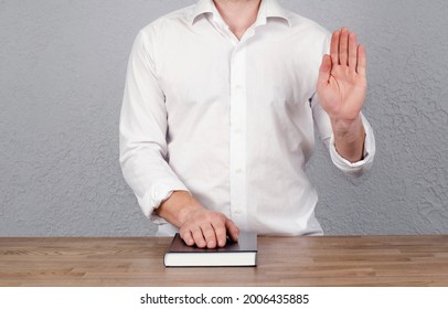 Oath. Young Man In A Shirt With A Raised Hand. Open Bible. Oath And Promise. Covenant. Agreement. Hand On The Bible Book.