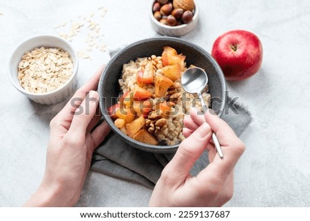 Oatmeal bowl with apple and cinnamon in woman's hands. Concept of vegan diet, clean eating, guilt free dessert Apple Pie Oatmeal for breakfast