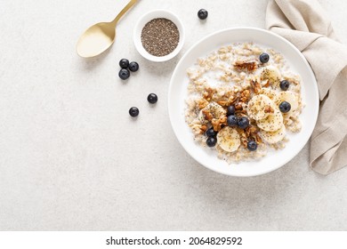 Oatmeal bowl. Oat porridge with banana, blueberry, walnut, chia seeds and almond milk for healthy breakfast or lunch. Healthy food, diet. Top view.  - Shutterstock ID 2064829592