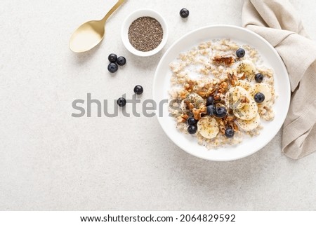 Oatmeal bowl. Oat porridge with banana, blueberry, walnut, chia seeds and almond milk for healthy breakfast or lunch. Healthy food, diet. Top view. 