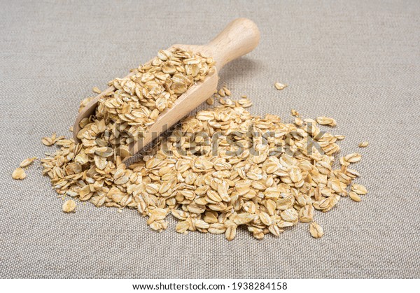 oatmeal\
cereal. scoop and pile of oatmeal with its plant. Dry rolled\
oatmeal. wooden scoop spoon with Oat\
flakes.