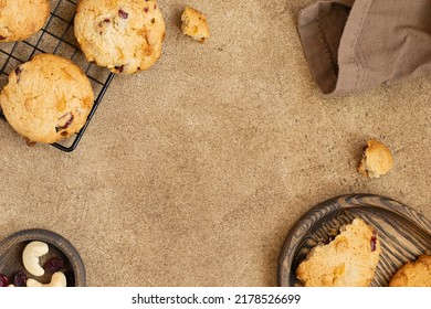 Oatmeal Cookies With Cranberry, Cashew And White Chocolate. Bottle Of Milk, Cooling Rack With Cookies, Kitchen Towel, Nuts And Cotton Flower. Brown Background, Space For Text. Food Frame