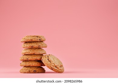 Oatmeal cookies with pieces of chocolate stand like a tower on a pink background