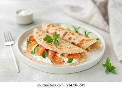 oatmeal pancakes with salted salmon, cucumber, greens and curd cheese, close-up
