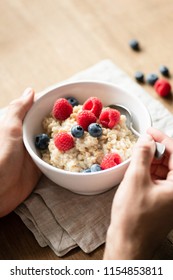 Oatmeal Porridge With Berries In Hands. Person Eating Healthy Breakfast