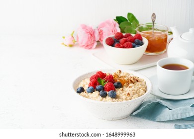 Oatmeal Porridge With Blueberry, Raspberries, Jam And Nuts In White Bowl, Dash Diet With Berries, White Background, Side View, Copy Space. Healthy Diet Breakfast