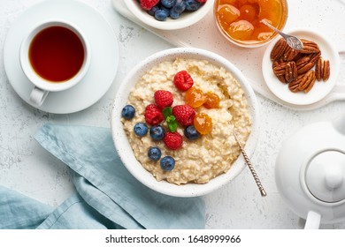 Oatmeal Porridge With Blueberry, Raspberries, Jam And Nuts In White Bowl, Dash Diet With Berries, White Background, Top View. Healthy Diet Breakfast