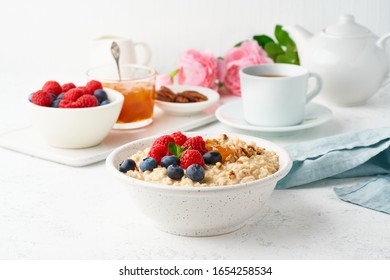 Oatmeal Porridge With Blueberry, Raspberries, Jam And Nuts In White Bowl, Dash Diet With Berries, White Background, Side View. Healthy Diet Breakfast