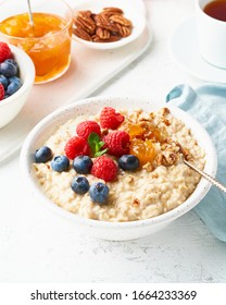 Oatmeal Porridge With Blueberry, Raspberries, Jam And Nuts In White Bowl, Dash Diet With Berries, White Background, Side View, Vertical. Healthy Diet Breakfast