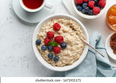 Oatmeal Porridge With Blueberry, Raspberries, Jam And Nuts In White Bowl, Dash Diet With Berries, White Background, Top View Copy Space. Healthy Diet Breakfast