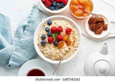 Oatmeal Porridge With Blueberry, Raspberries, Jam And Nuts In White Bowl, Dash Diet With Berries, White Background, Top View. Healthy Diet Breakfast