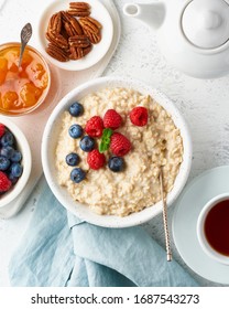 Oatmeal Porridge With Blueberry, Raspberries, Jam And Nuts In White Bowl, Dash Diet With Berries, White Background, Side View, Vertical. Healthy Diet Breakfast