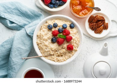 Oatmeal Porridge With Blueberry, Raspberries, Jam And Nuts In White Bowl, Dash Diet With Berries, White Background, Top View. Healthy Diet Breakfast