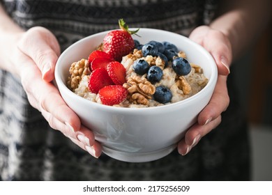 Oatmeal Porridge Bowl With Berries In Female Hands. Vegan Food, Clean Eating, Dieting Concept. Woman's Health