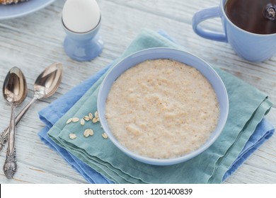 Oatmeal Porridge Bowl With Black Tea And Boiled Egg On The White Wooden Background. Healthy Nutritious Breakfast. Concept Of Healthy Eating, Dieting. 