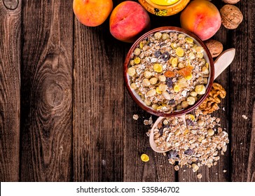 oatmeal in a sac, dried apricots, raisins, grapes, nuts on the background of wooden planks and sacking