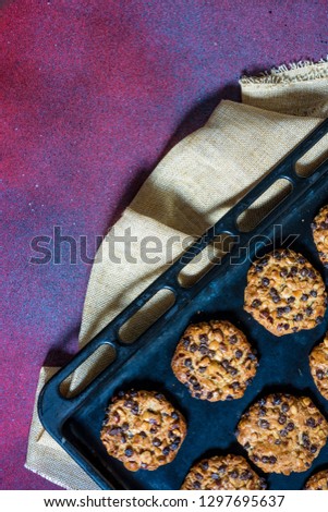 oats cookies with hazelnuts and chocolate chips on a baking sheet and a cloth