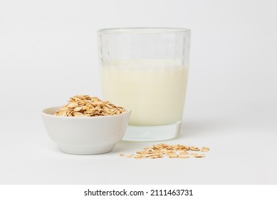 Oats As Popular Ingredient For Variant Of Vegetable Milk. Dry, Raw Oat Flakes In Bowl And Milk In A Glass Ingredients For Making Oatmeal Porridge On  White Background 