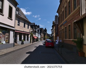 Oberwesel, Germany - 07-18-2021: Diminishing Perspective Of Street In Oberwesel Town Center With Parking Cars, Shops And Historic Buildings On Sunny Summer Day With Blue Sky.