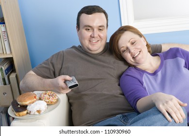 Obese Couple Watching Television At Home