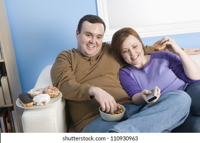 Obese Couple Watching Television At Home