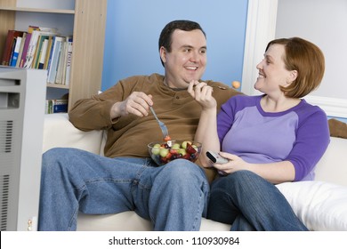 Obese Couple Watching Television At Home