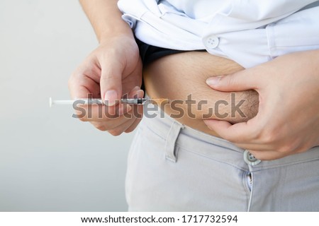 Obese diabetes man injecting insulin into his belly. Subcutaneous injection technique, Selective focus.