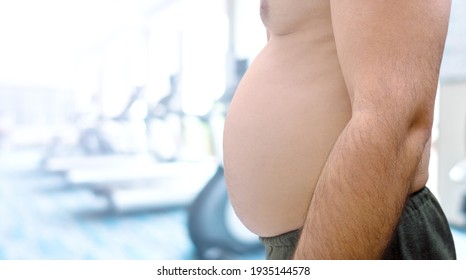 Obese Man With Excessive Belly Fat On Gym Background. Sports Lifestyle Concept To Reduce Belly And Shape Up Healthy Stomach Muscle.