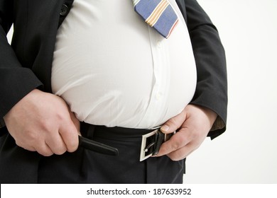 An obese man in a suit struggles to fasten his belt.