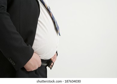 Obese Man In A Suit Struggling To Fasten Belt, Seen In Profile.