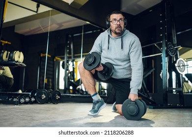 Obese Middle Aged Men Training While Using Dumbbells In The Gym. Overweight Man Trying To Lose Weight. Warming Up.