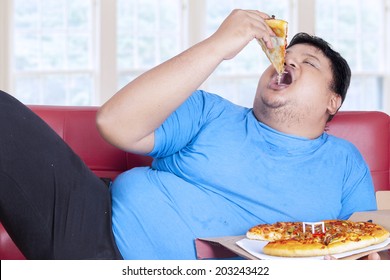 Obese Person Eats Pizza While Sitting On Couch At Home